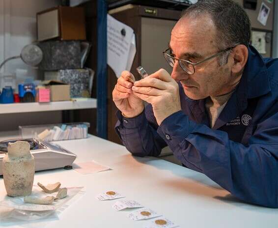 ד"ר רוברט קול בוחן את מטבעות הזהב // צילום: שי הלוי, רשות העתיקות